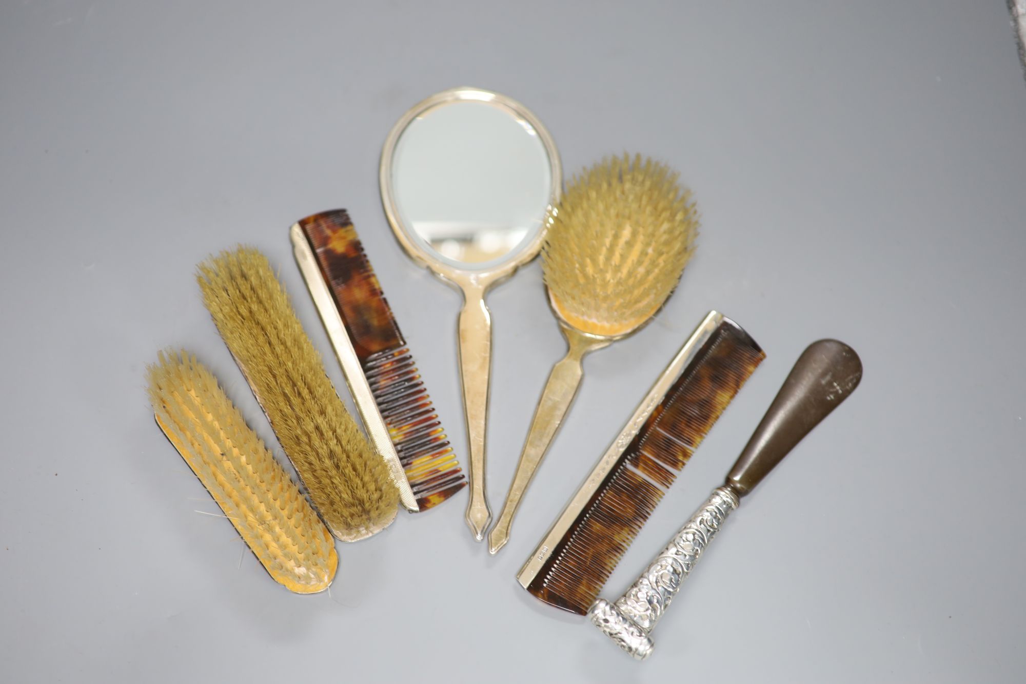 A four-piece engine-turned silver dressing table set, an embossed silver-backed clothes brush, a similar shoe horn and a comb